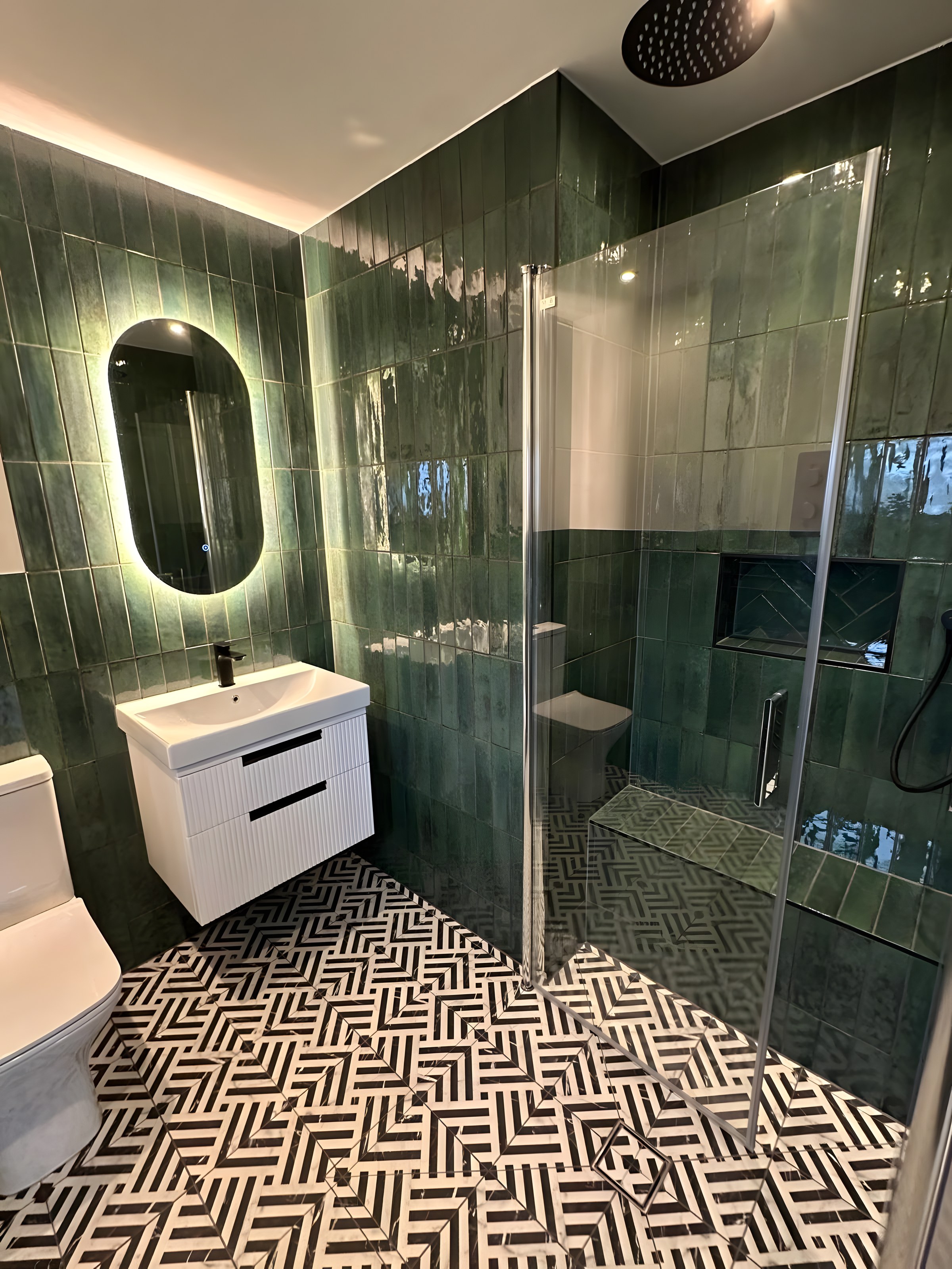 Shower room with green glazed tiles, backlit oval mirror and walk-in shower