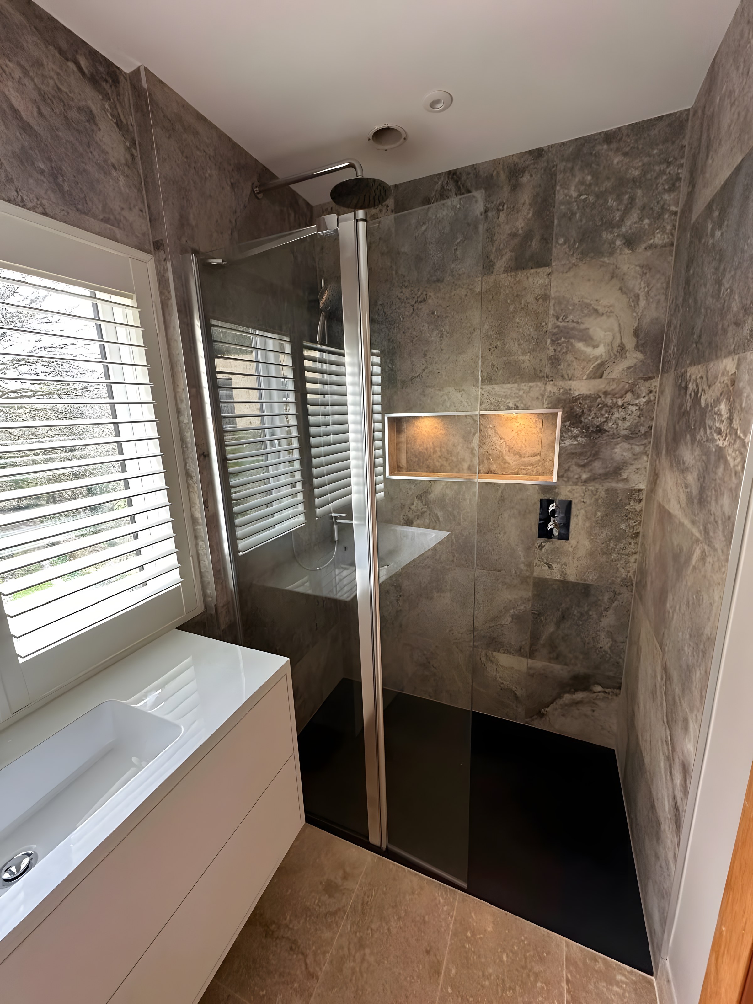 Travertine-tiled shower with lit niche