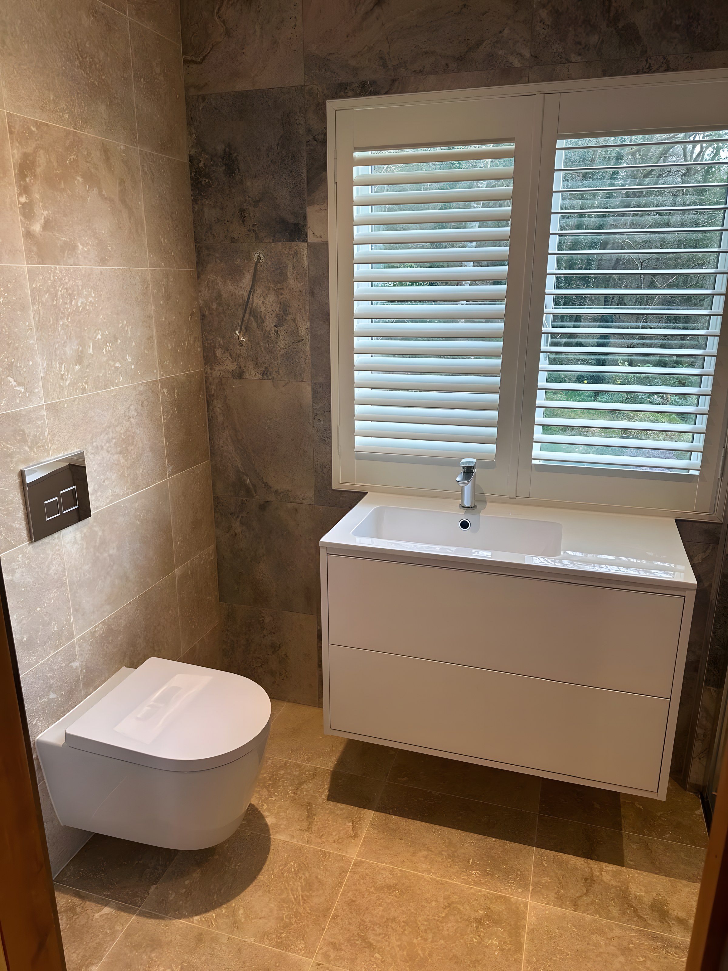Travertine shower room with wall-hung WC
