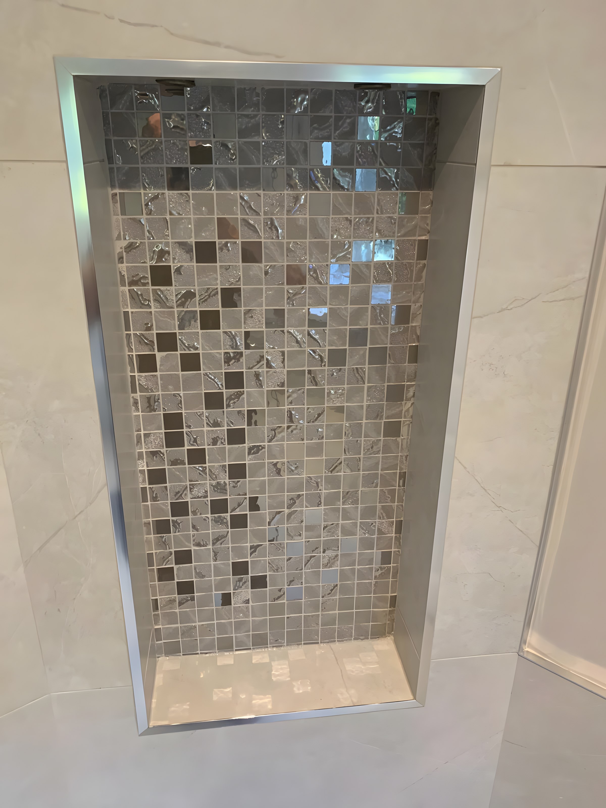 Mosaic-lined shower niche with steel trim