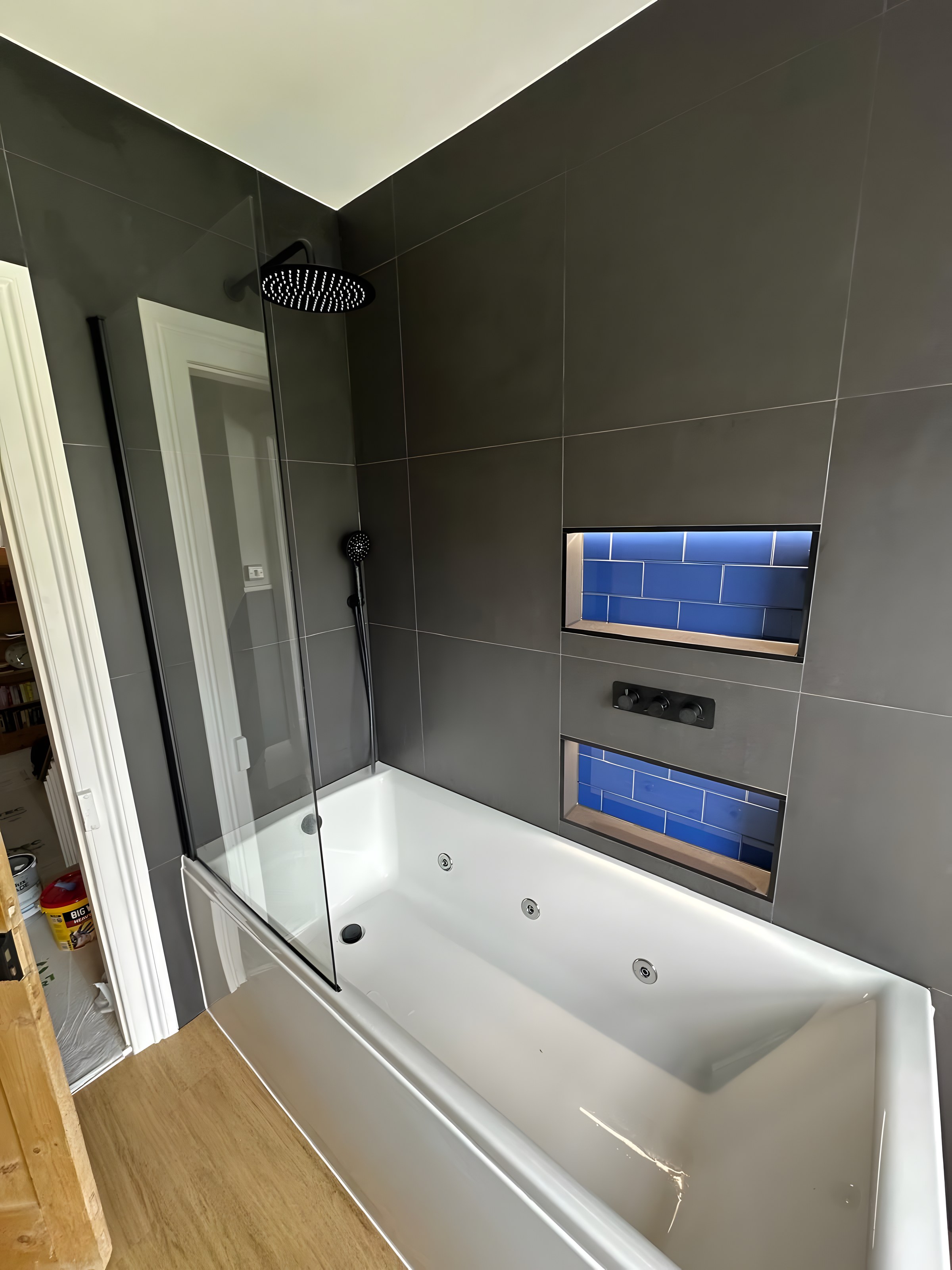 Whirlpool bath with large-format dark tiles
